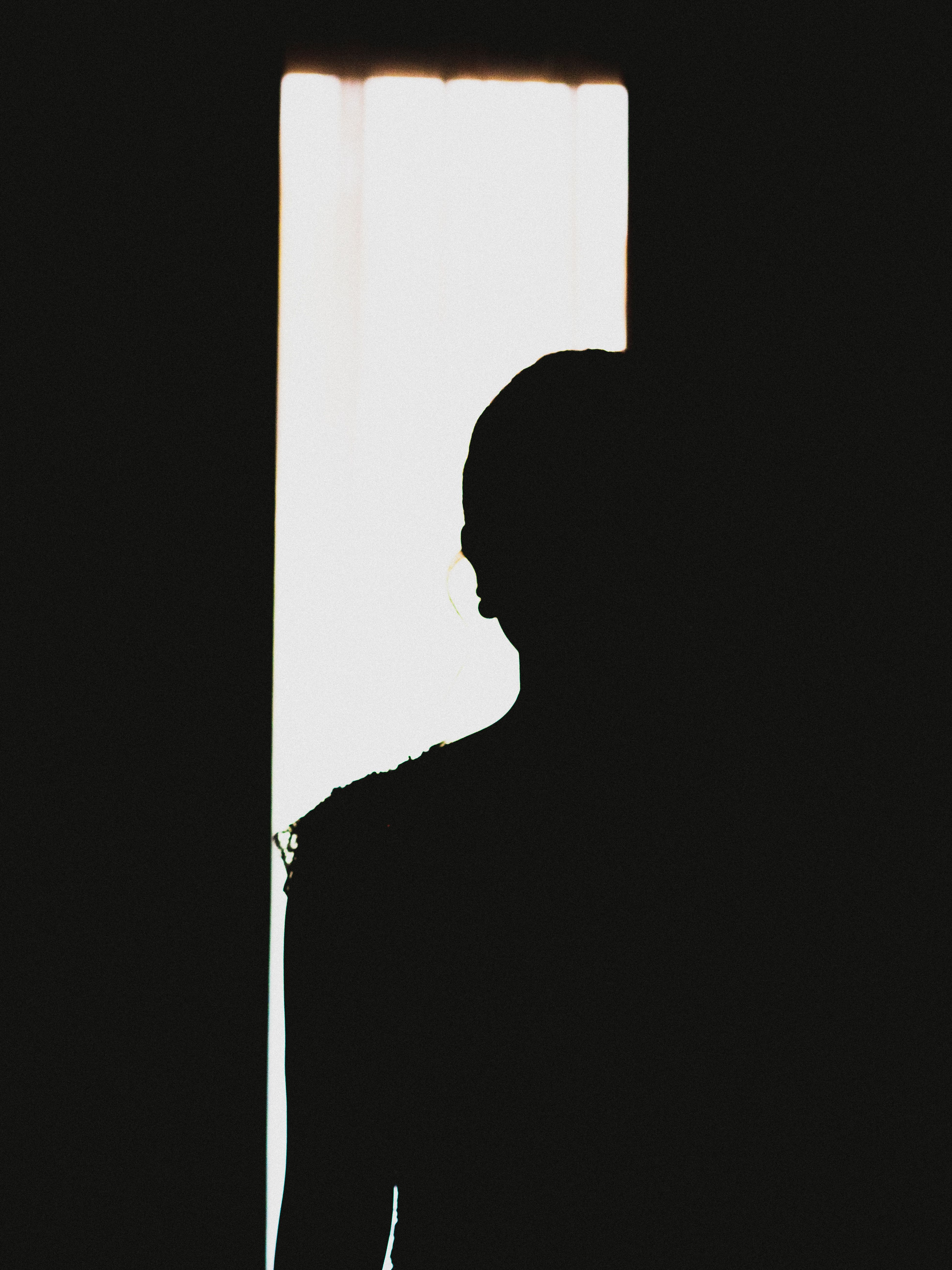 Dramatic silhouette of a woman framed against a bright doorway, captured in low light